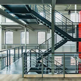 Industrial building interior with red wall and black, metal staircase